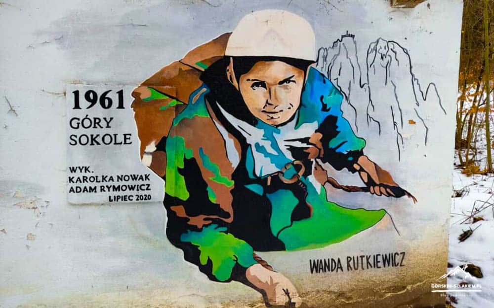 Colorful street mural of a climber in a hooded jacket, with Polish text and 'Wanda Rutkiewicz' signed on the wall.